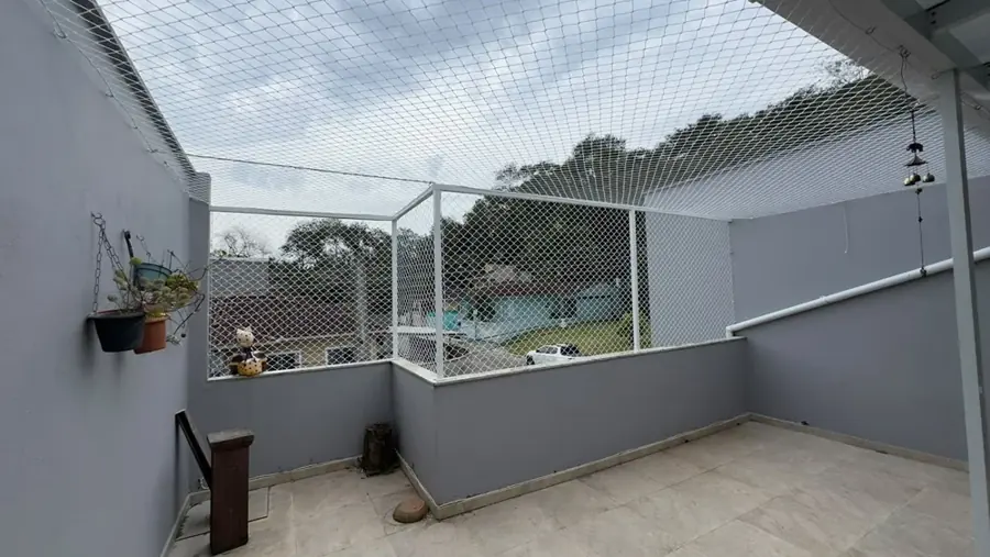 Área externa residencial coberta com rede e estrutura branca pela Telas SC